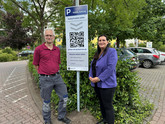 Bargeldlos bezahlen: Jennifer Westendorf und Frank Lumplesch vor der neuen Beschilderung zum Start des neuen Parkraumbewirtschaftungssystems.